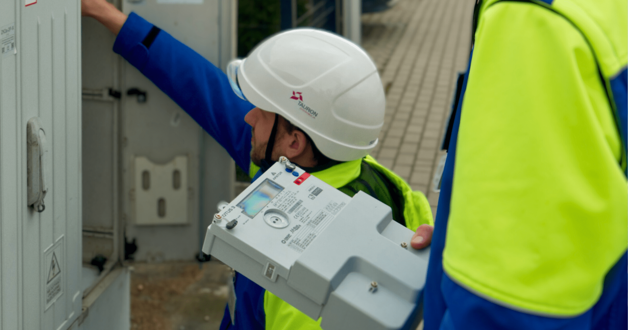 elektromonter mocuje w szafce licznik zdalnego odczytu energii elektrycznej