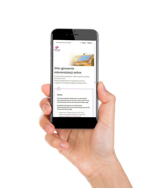 W ręce mężczyzny znajduje się smartfon, na którego ekranie wyświetla się formularz zgłoszenia mikroinstalacji online