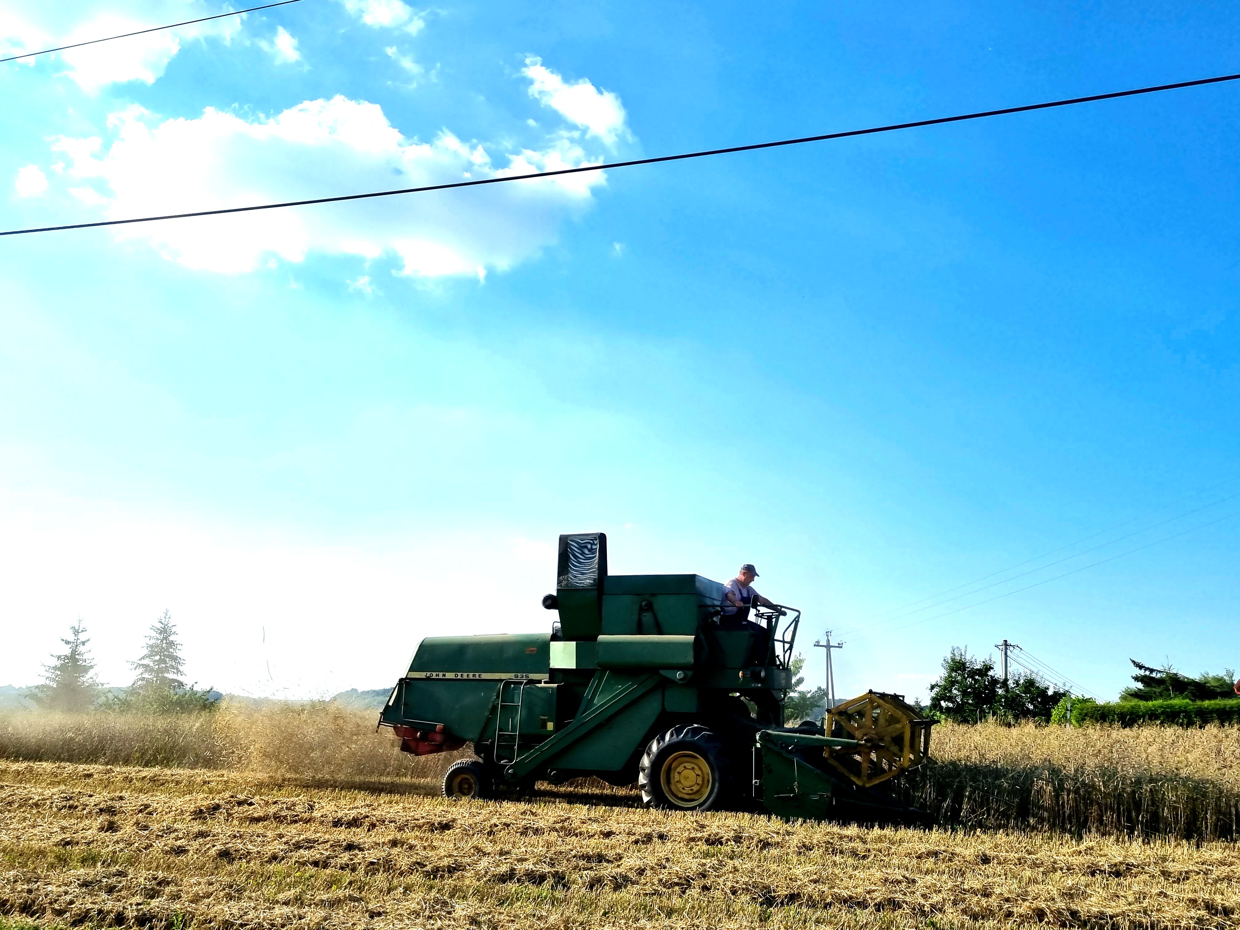 rolnik prowadzi kombajn podczas pracy w polu w bliskiej odległości od zwisającego przewodu z linii energetycznej