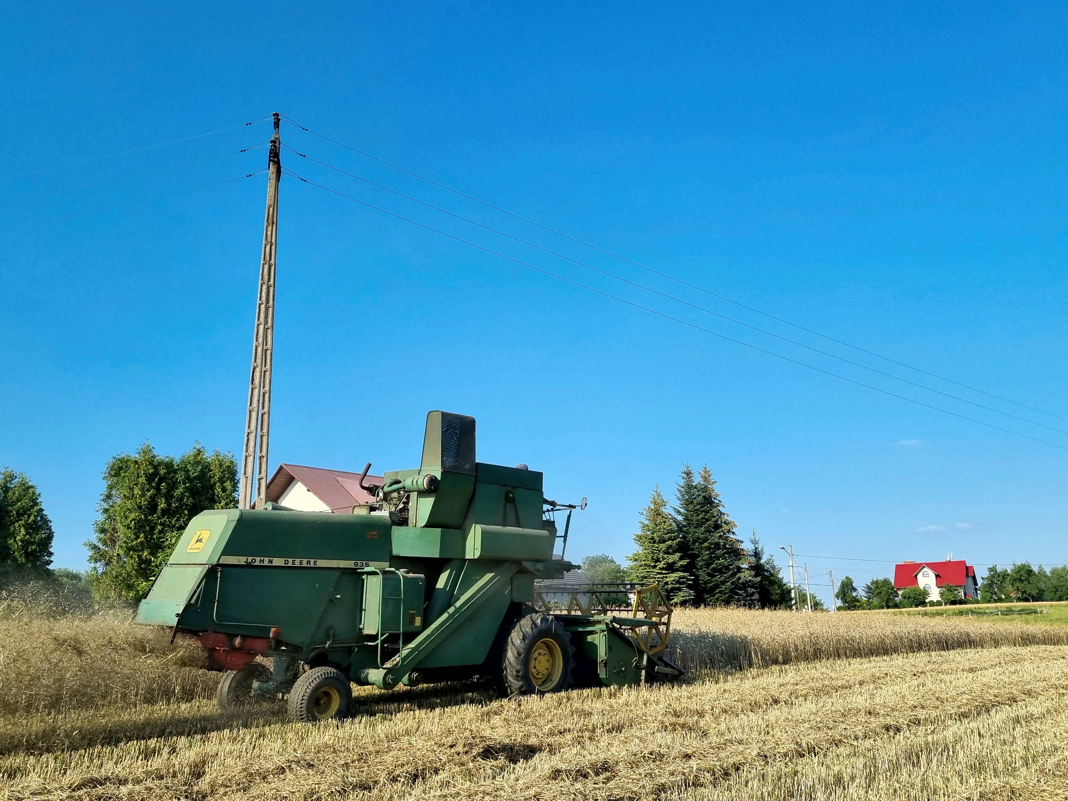 kombajn przejeżdża niedaleko od słupa energetycznego linii niskiego napięcia