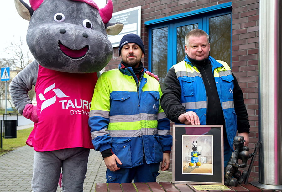 przy figurce Beboka Sztromka stoi dwóch pracowników pogotowia energetycznego oraz maskotka byczek Tauronek