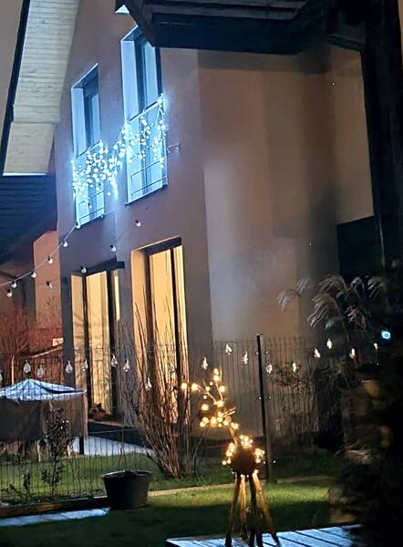 nocny widok ściany domu o białej fasadzie, na której widoczne jest świąteczne oświetlenie