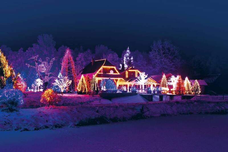 zimowy, nocny widok udekorowanych w świąteczne oświetlenie domów i drzew rosnących przy tych domach