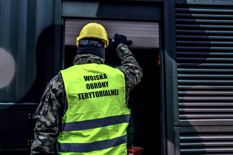 żołnierz Wojsk Obrony Terytorialnej stoi przed mobilnym agregatem prądotwórczym