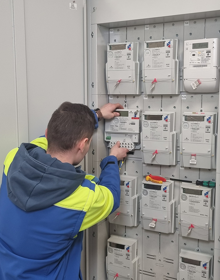 elektromonter mocuje w szafce licznik zdalnego odczytu energii elektrycznej