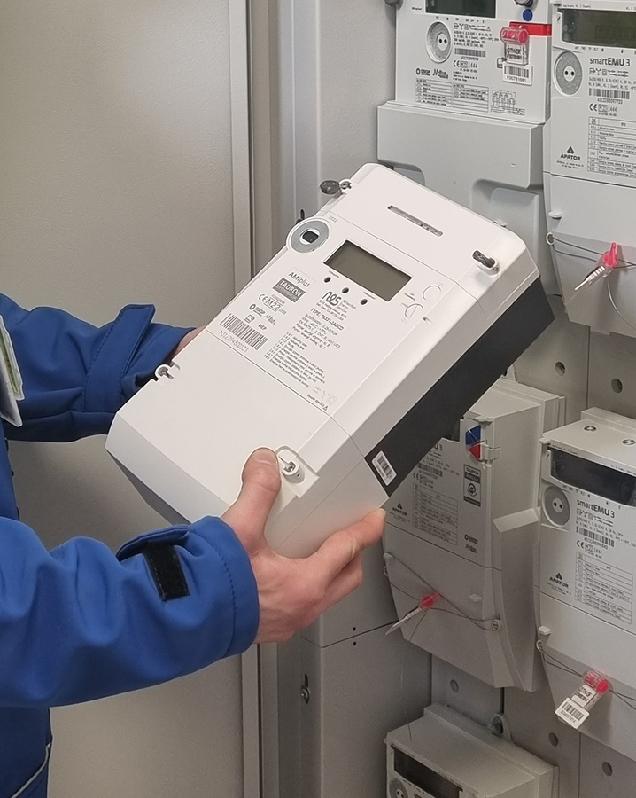 elektromonter trzyma w rękach licznik zdalnego odczytu energii elektrycznej