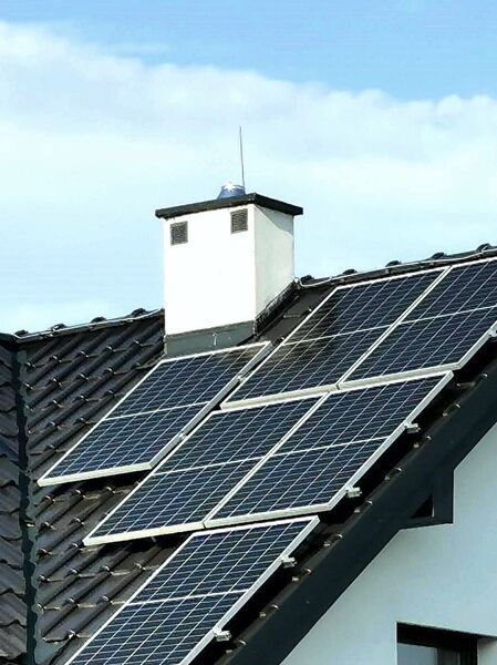 panele fotowoltaiczne na szarym dachu domu jednorodzinnego