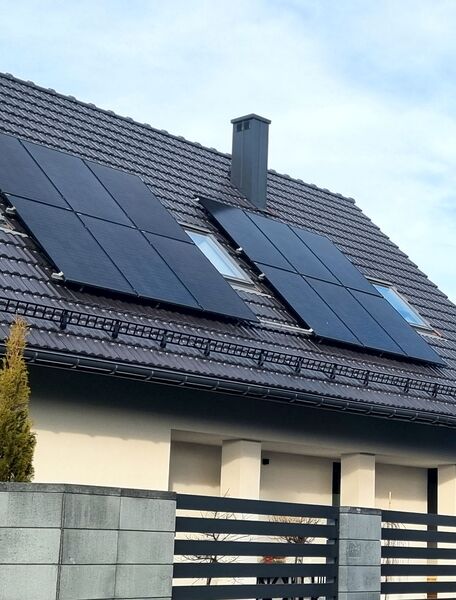 panele fotowoltaiczne na szarym dachu domu jednorodzinnego