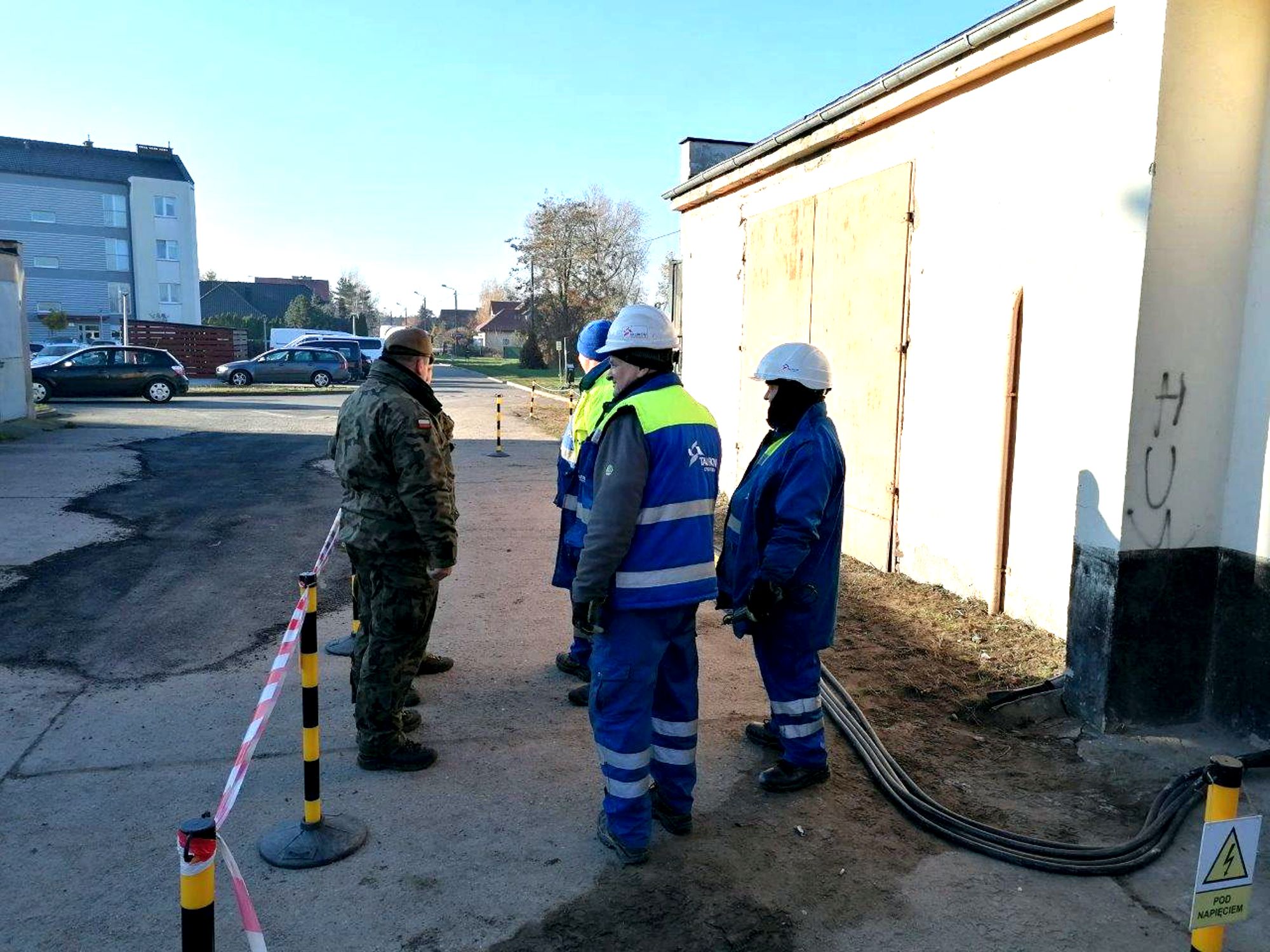 grupa żołnierzy i pracowników Tauron Dystrybucji stoją przy stacji transformatorowej