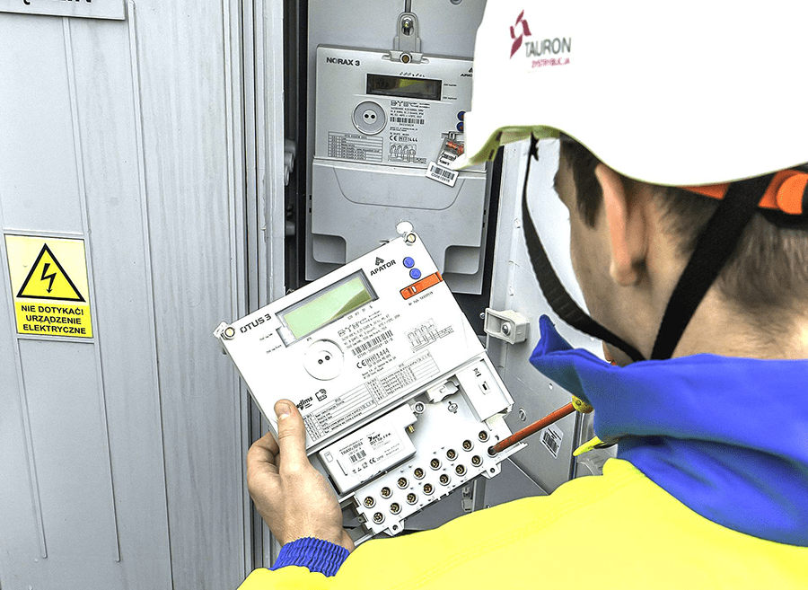 pracownik TAURON Dystrybucji wymienia licznik energii elektrycznej na nowy