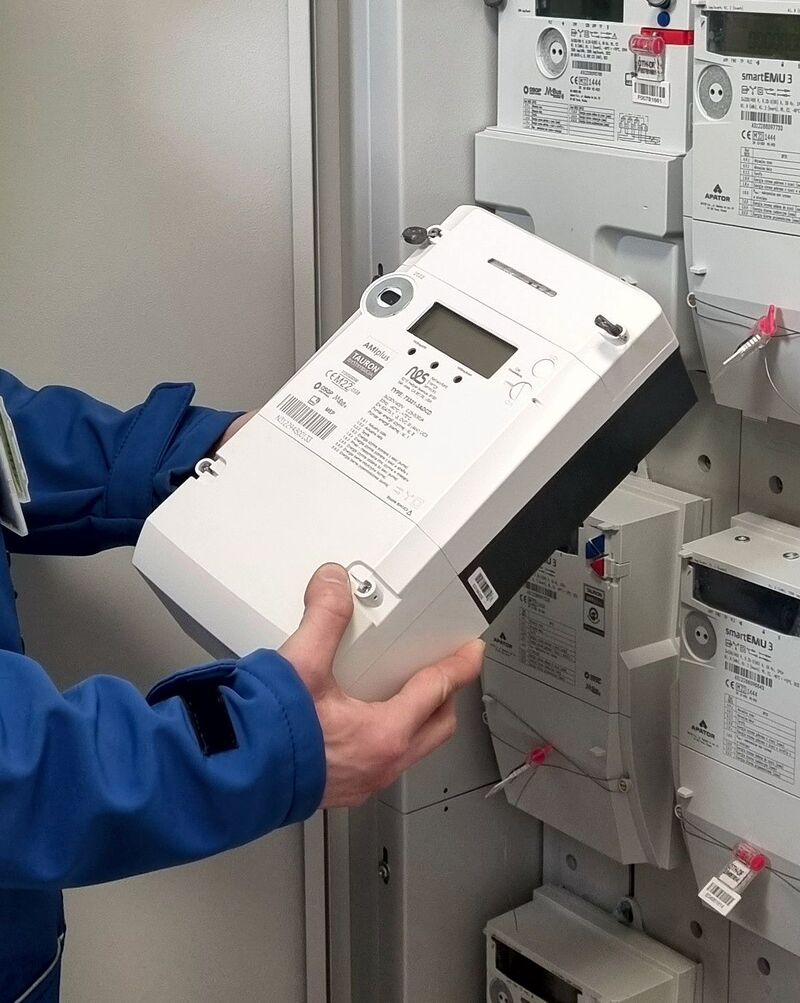 elektromonter trzyma w rękach licznik zdalnego odczytu energii elektrycznej
