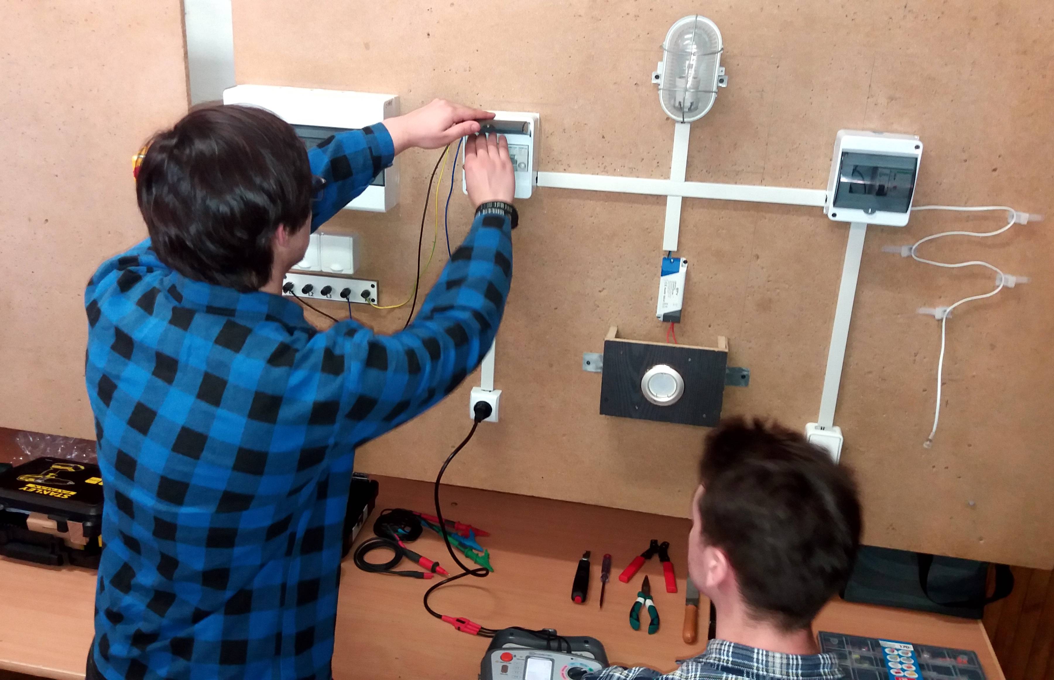 dwóch uczniów manipuluje przy pulpicie z umieszczonymi na nim elementami elektronicznymi
