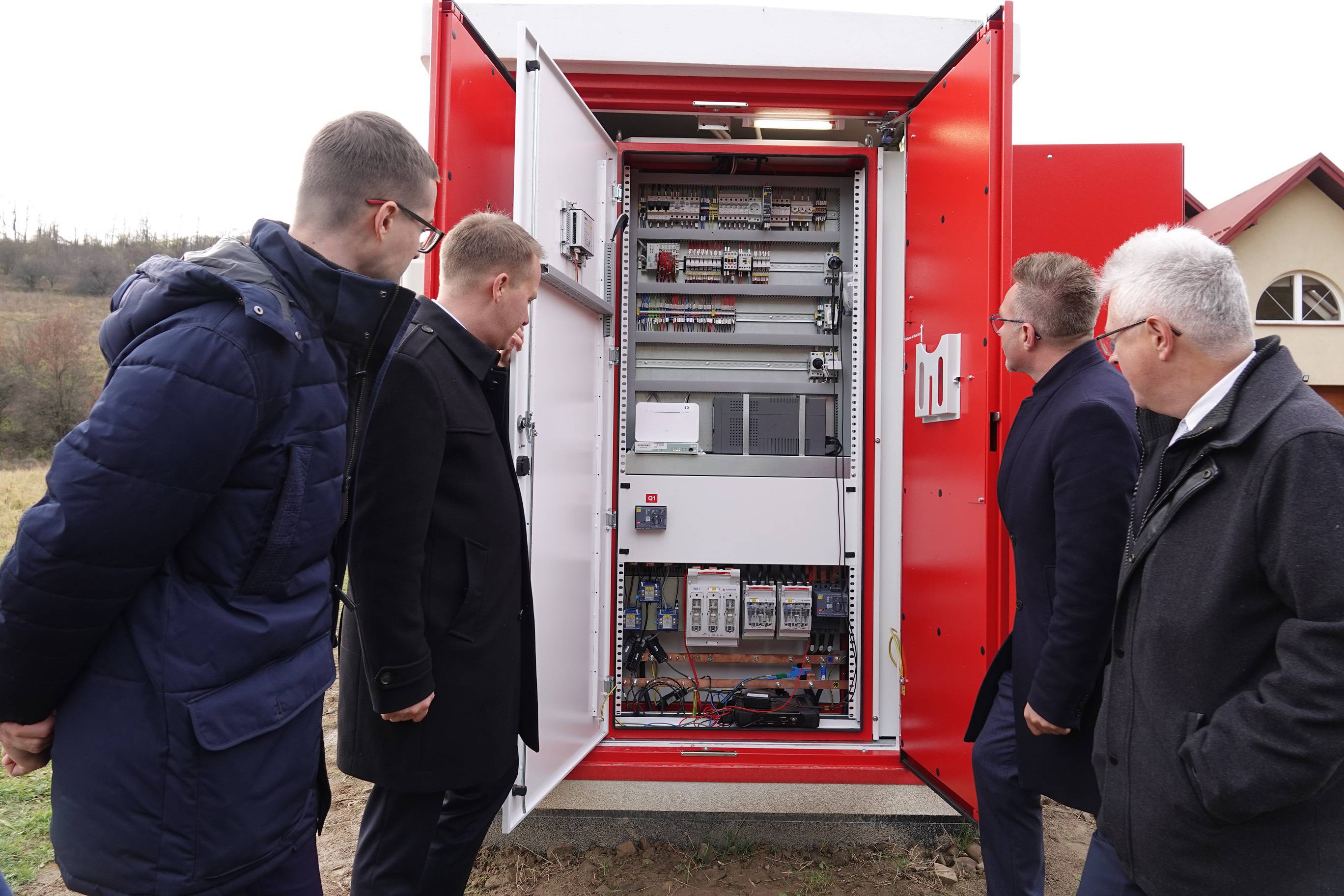 Grupa czterech mężczyzn wpatruje się w wnętrze otwartej budowli magazynu energii